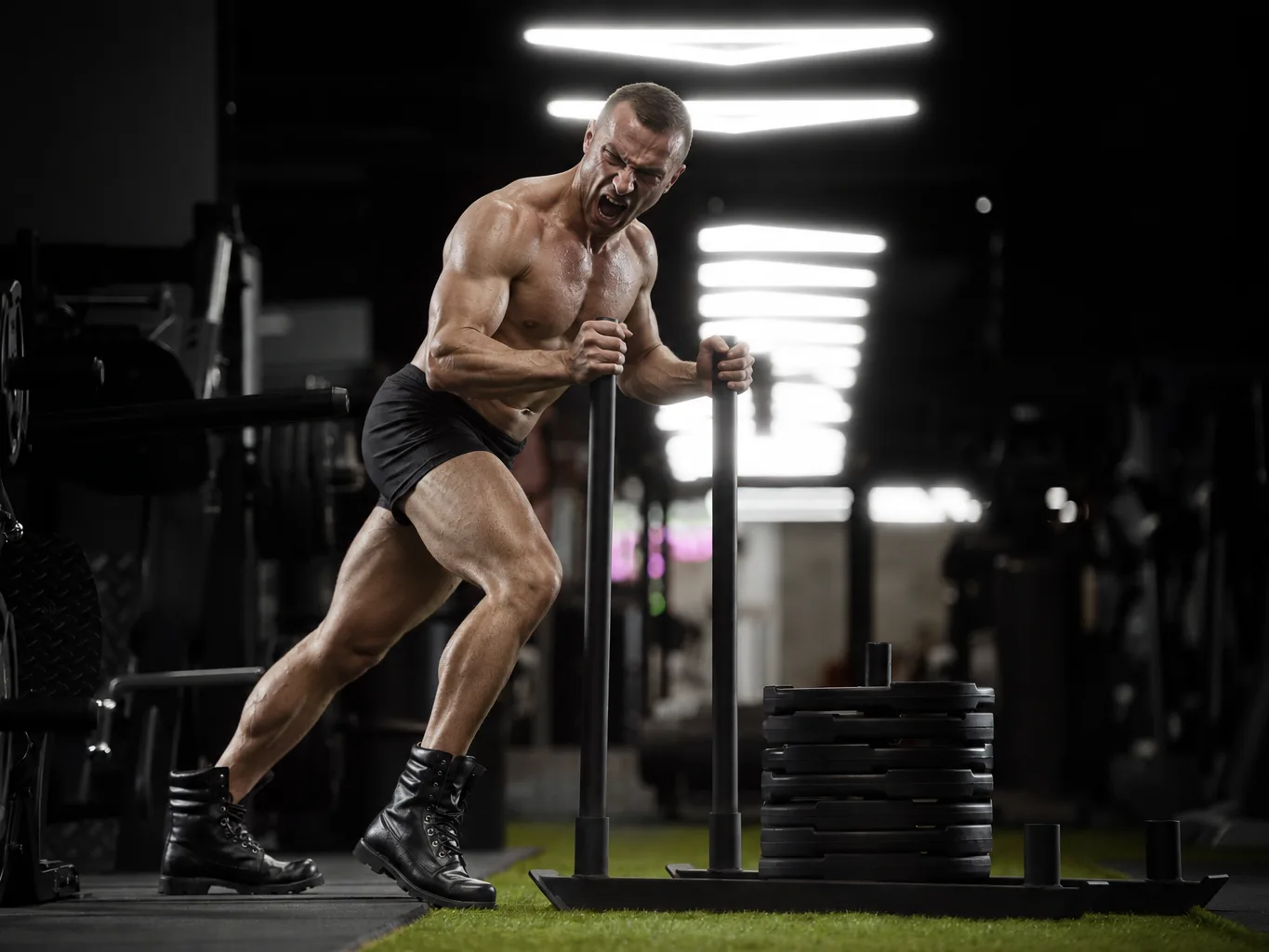 Атлет толкает сани с блинами — тренировка HYROX в IRON FITNESS