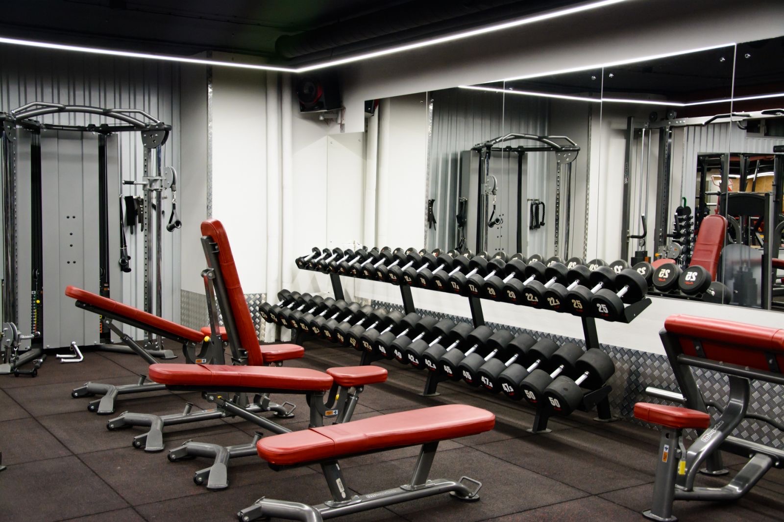 Гантельный ряд и регулируемые скамьи перед зеркалами в IRON FITNESS
